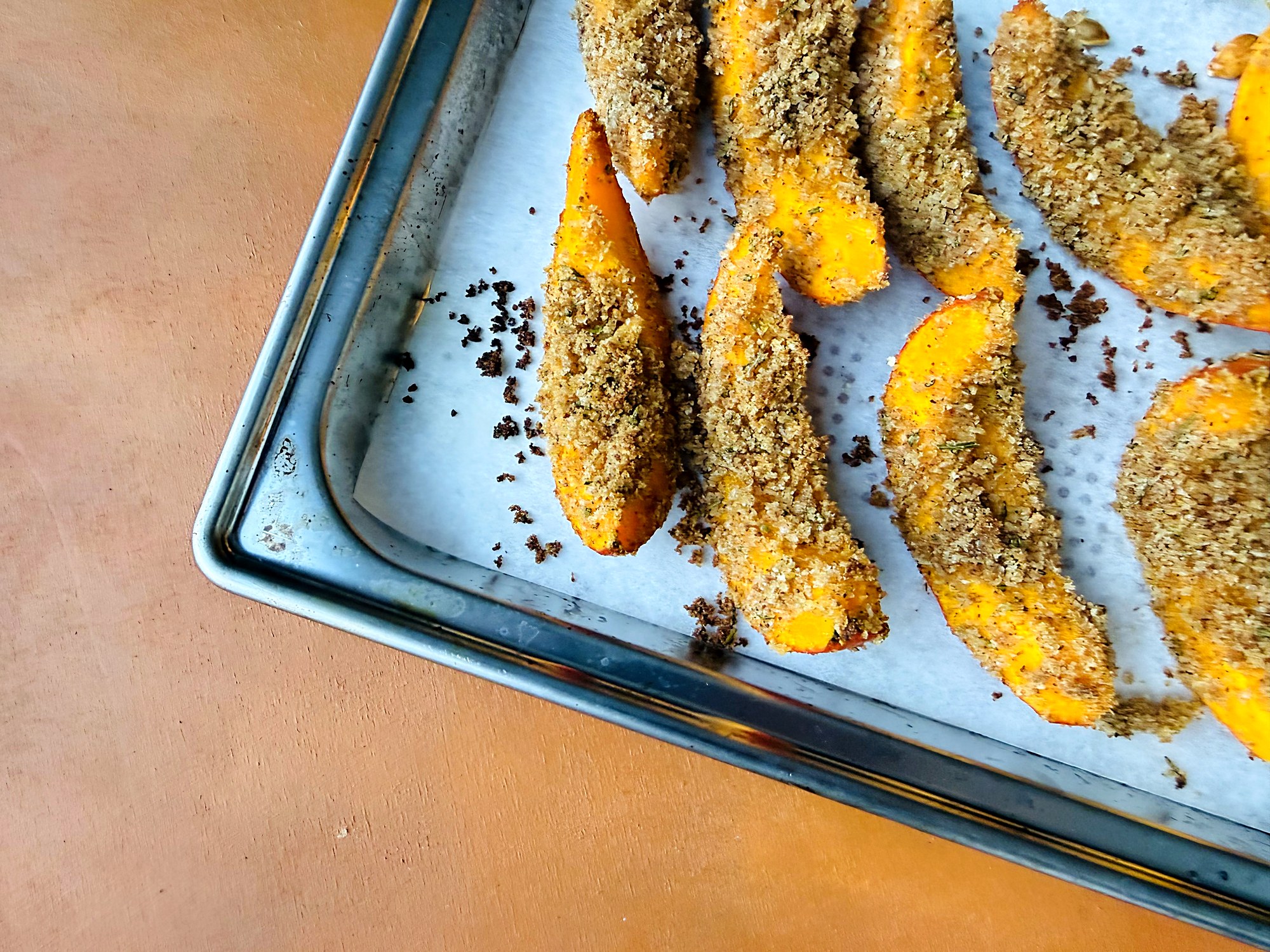Kürbisschnitze mit Kräuterpanade auf dem Backblech